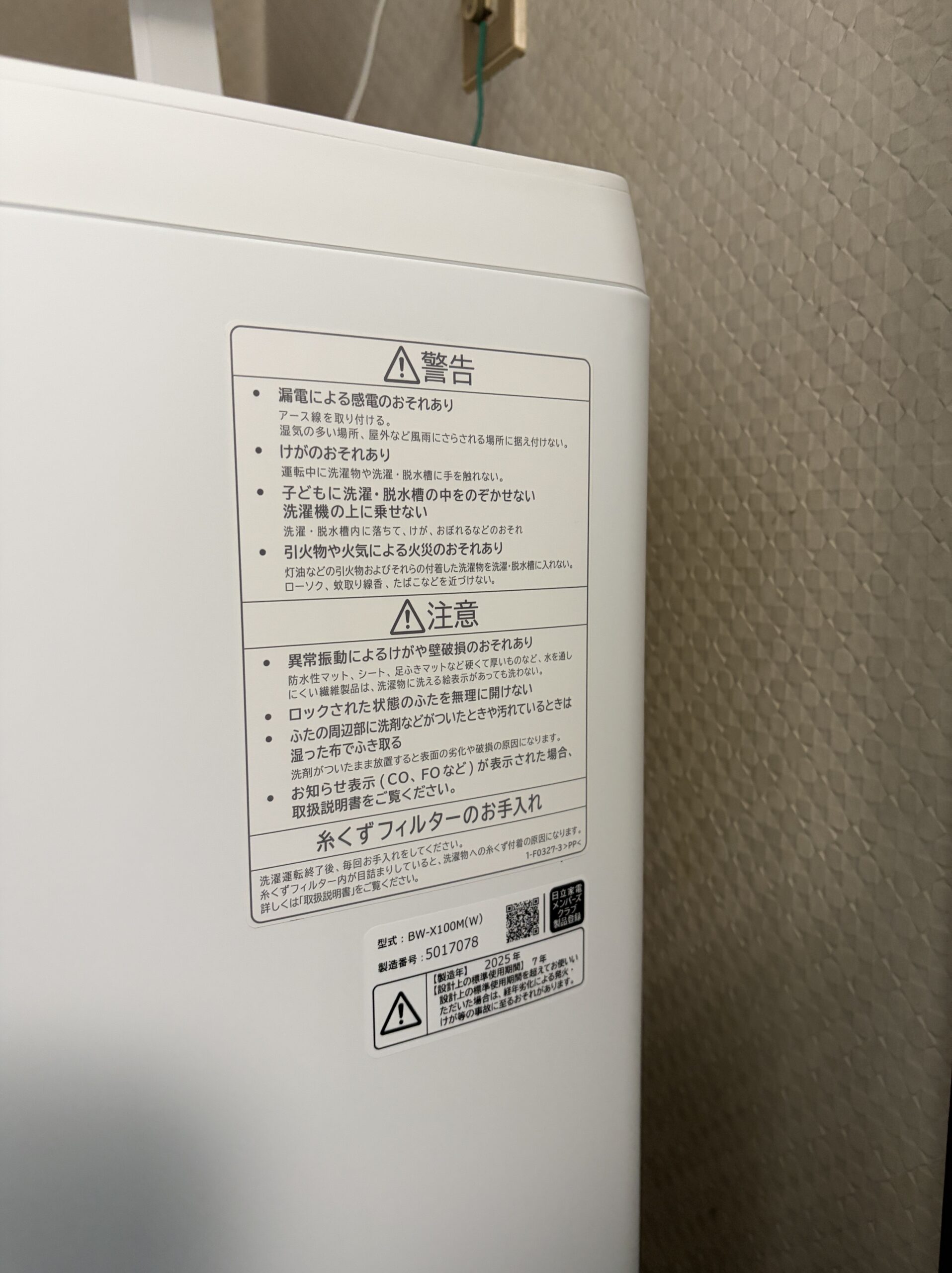 洗濯機の側面に貼られた型式と製造番号、製造年が印字された表示ラベルのクローズアップ