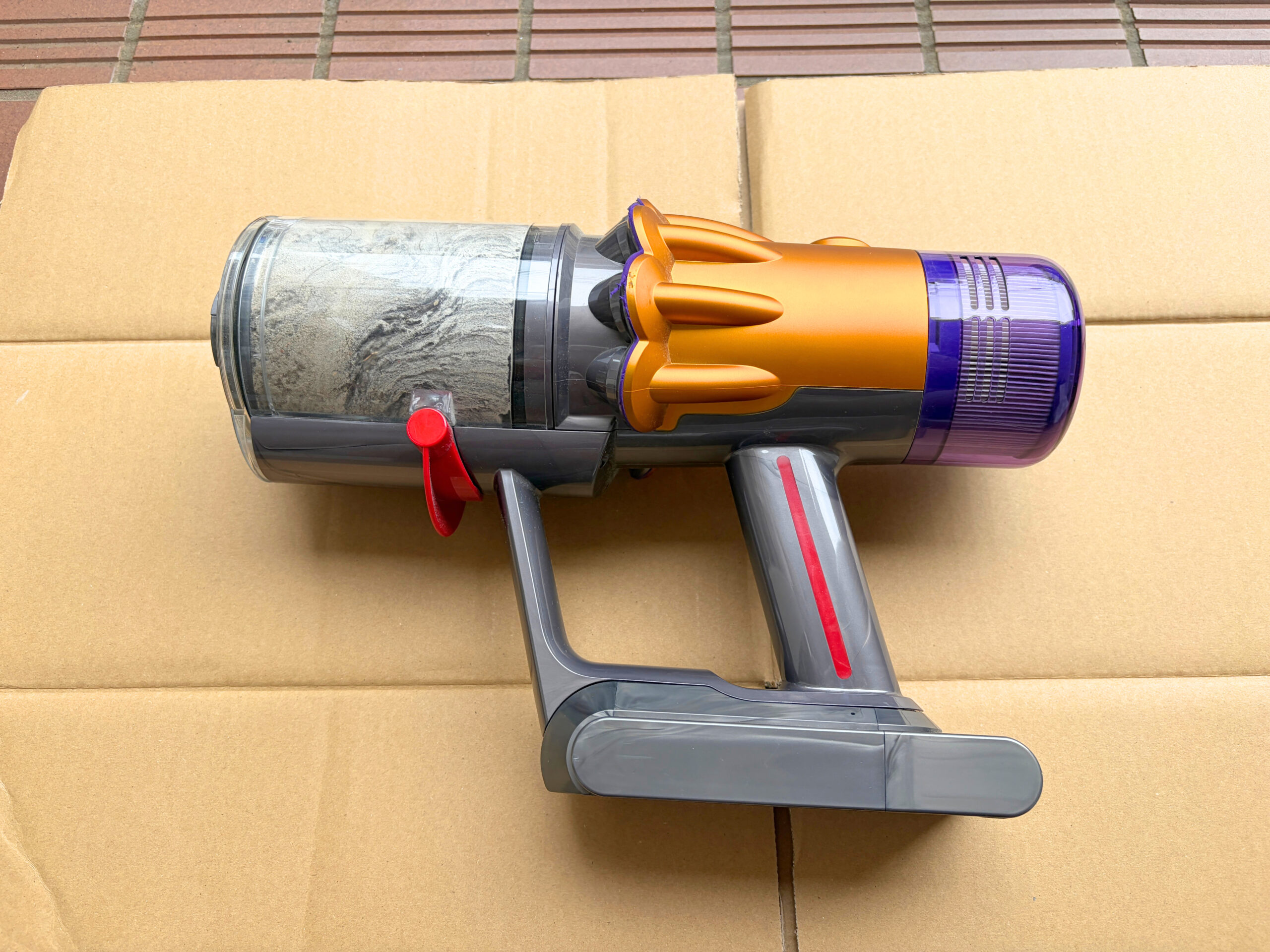 ダストビンにゴミやほこりがたまったDyson V12 Detect Slim Completeの本体を横から撮影した写真