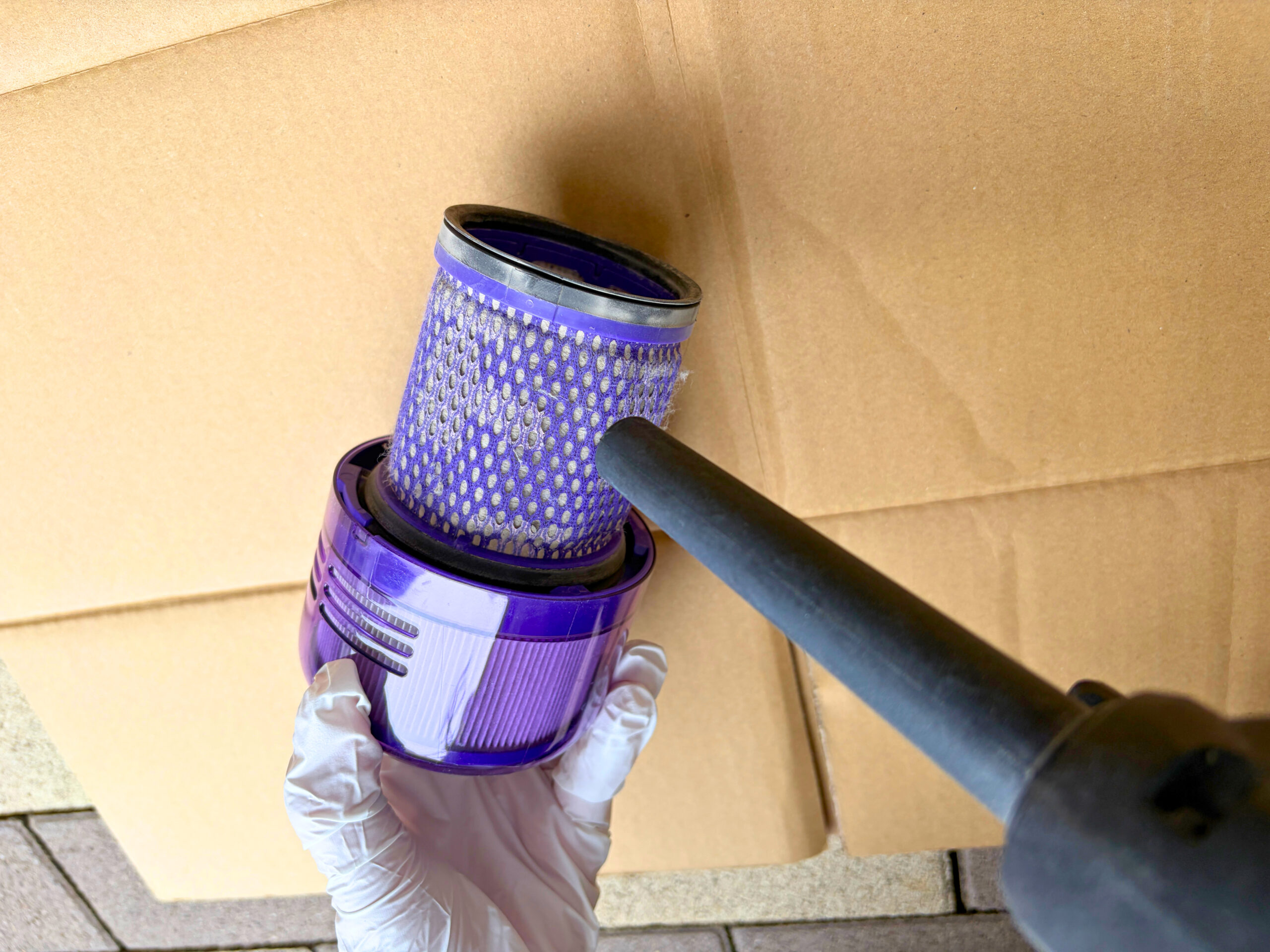 Dyson V12 Detect Slimから取り外したフィルターにエアダスターを当ててほこりを除去している様子