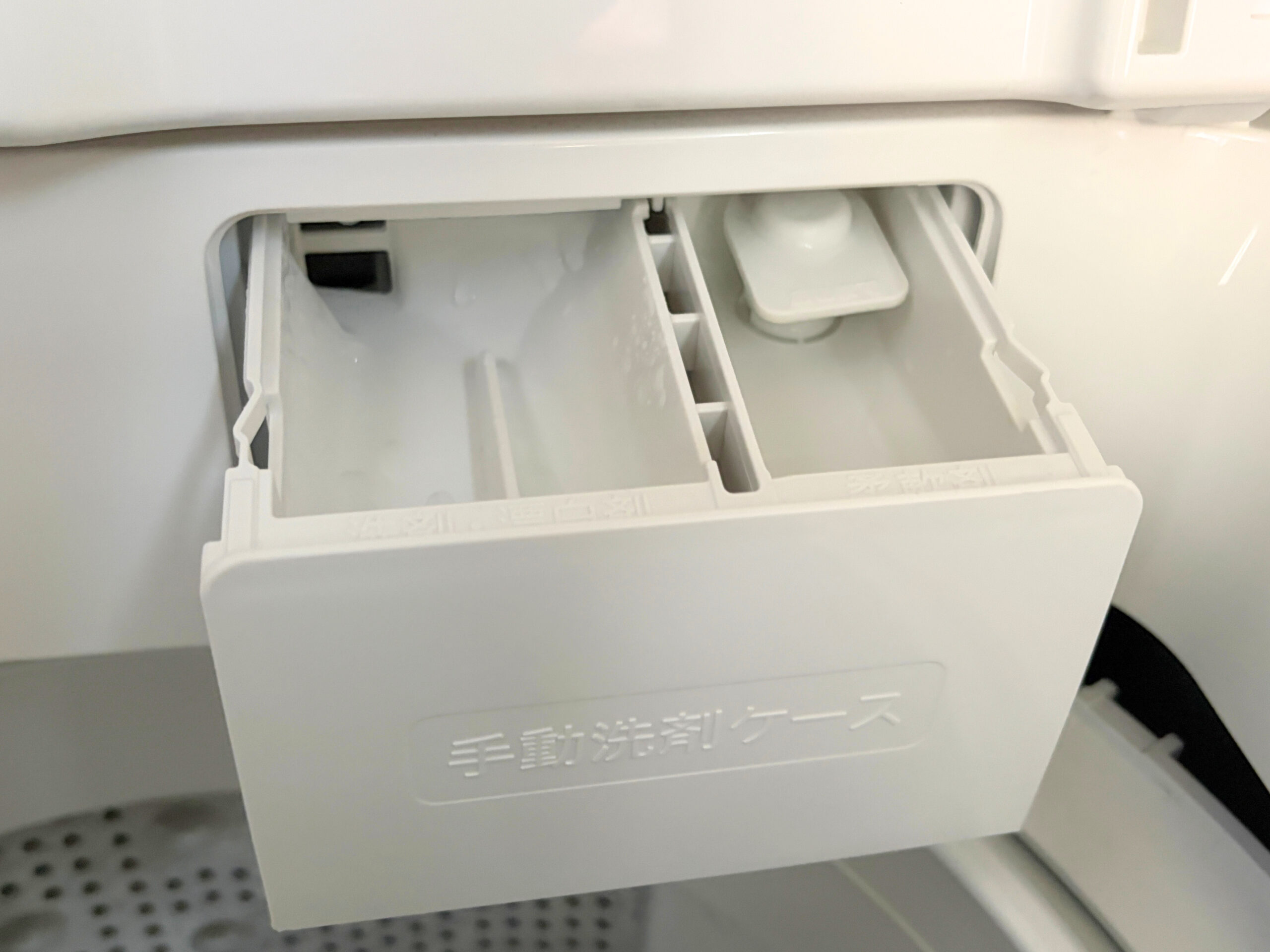 洗濯槽の上部から引き出した手動洗剤ケース 左側が洗剤と漂白剤用の区画で右側が柔軟剤用の区画