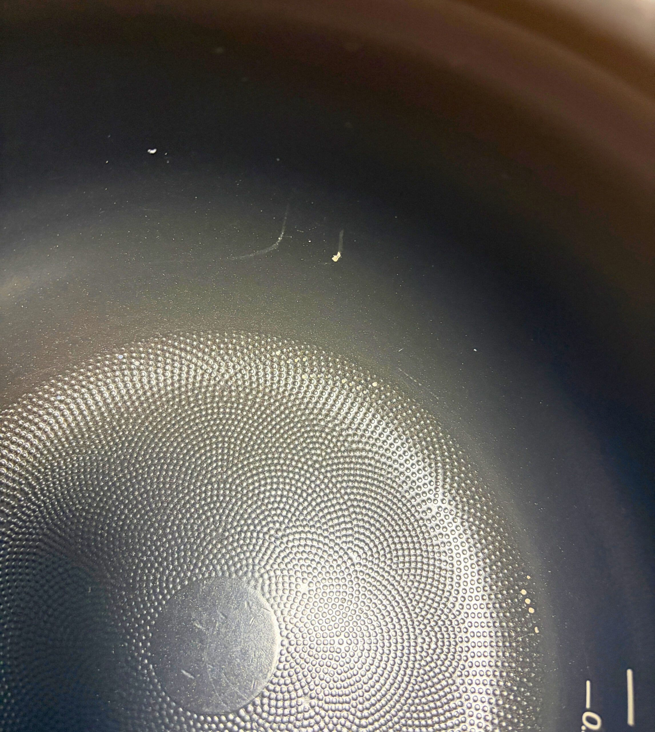 炊飯器の内釜の内側をアップで撮影し底面の凹凸と側面の細かな傷が見える様子