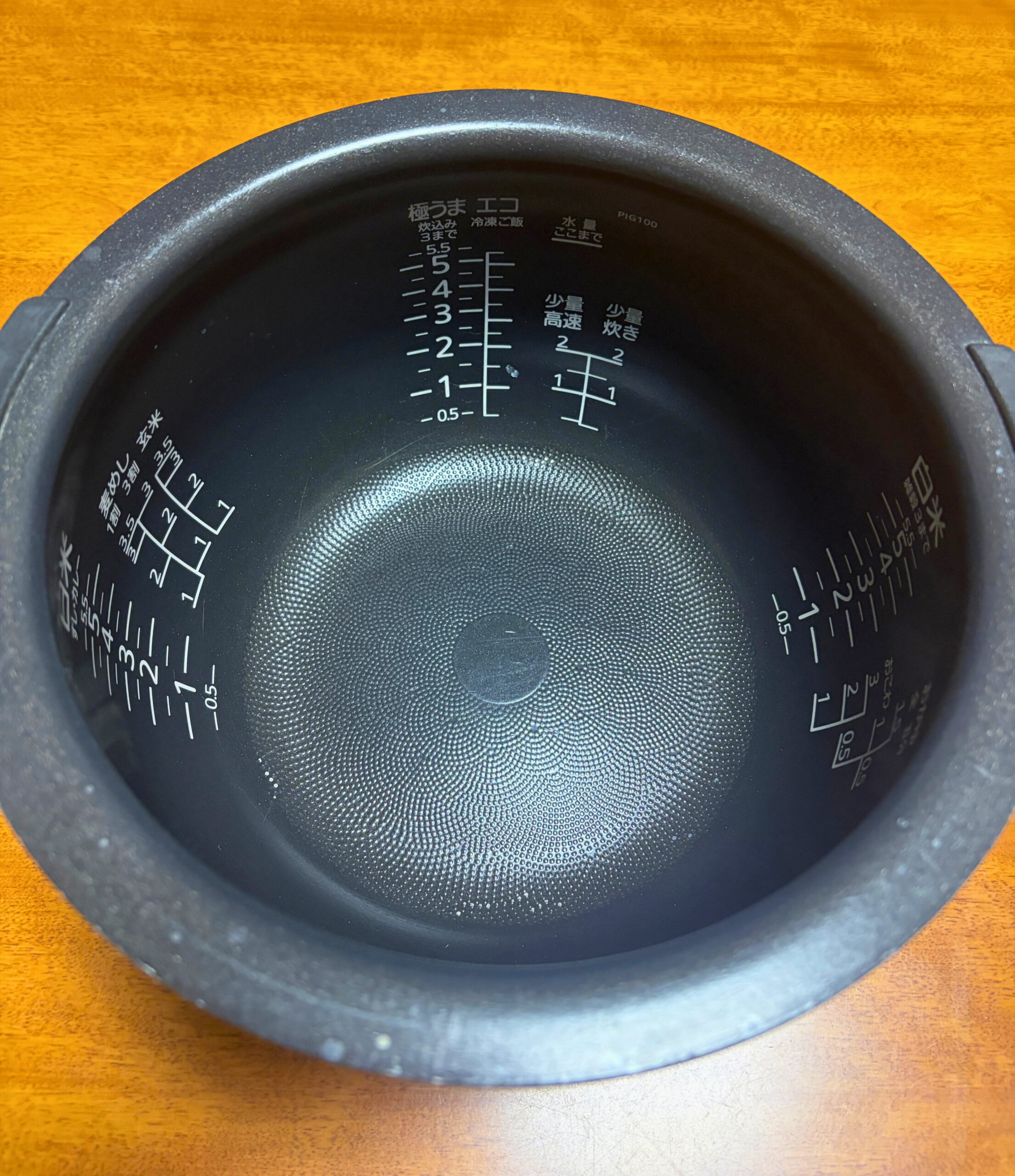 取り外した炊飯器の内釜を上から撮影し水位目盛りと底面の凹凸が見える様子